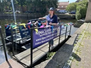 Image of Vicky Willis from Ripon Scenic Cruises from the Ripon BID blog Image of Vicky Willis in front of the Pride of Ripon Narrowboat photo credit Tim Flanagan